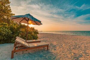 Beautiful tropical sunset scenery, two sun beds, loungers, umbrella under palm tree. White sand, sea view with horizon, colorful twilight sky, calmness and relaxation. Inspirational beach resort hotel photo