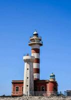 un faro en el playa con un azul cielo foto