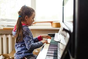 little girl plays the old piano in the old house photo