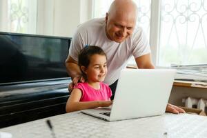 Granddaughter helping grandpa to make online communication on laptop photo