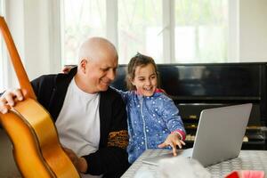 Granddaughter helping grandpa to make online communication on laptop photo