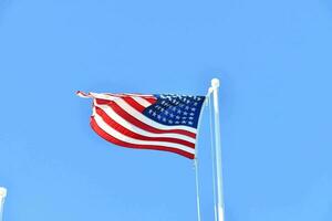 an american flag flying in the wind against a blue sky photo