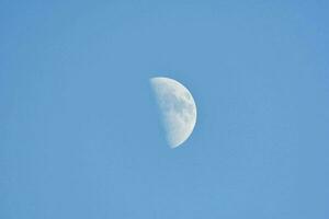 the moon is seen in a clear blue sky photo