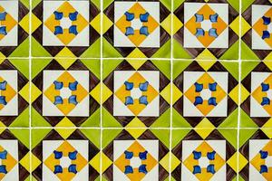 a colorful tile wall with a yellow, green and blue design photo