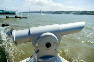 a silver binoculars is looking out over the water photo
