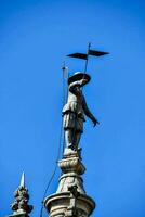 a statue of a man holding an umbrella on top of a building photo