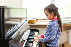 little girl plays the old piano in the old house photo