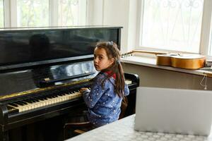 little girl plays the old piano in the old house photo
