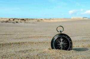 a compass is sitting in the sand on a beach photo