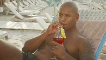 Handsome man drinking cocktail while relaxing at the beach video