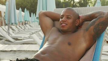 Handsome man sunbathing at the beach video