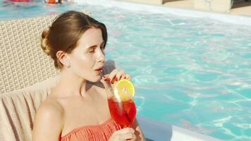 Beautiful happy woman enjoying drinking cocktail at the poolside video