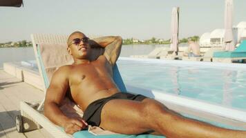 Handsome athletic man resting near the swimming pool at the beach video