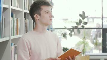 jovem homem desfrutando lendo uma livro às a biblioteca video