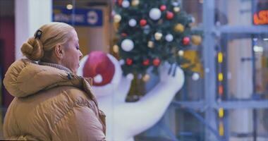 ein Mädchen Spaziergänge im ein groß Neu Jahre Einkaufen Center. Weihnachten Baum, Spielzeuge auf das Weihnachten Baum video