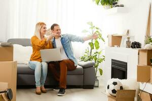 Beautiful couple sitting between many boxes in their new home photo