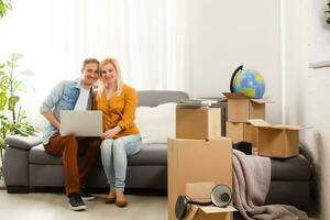 Beautiful couple sitting between many boxes in their new home photo