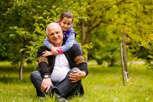 Portrait of small girl with senior grandfather in the backyard garden, standing. photo