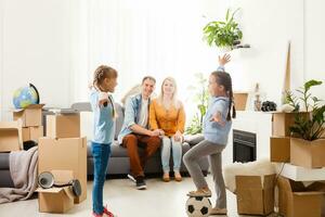 two little daughters celebrating moving day, excited by relocation into new house, laughing living room with cardboard boxes photo