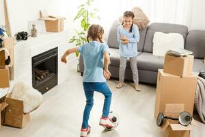 two little daughters celebrating moving day, excited by relocation into new house, laughing living room with cardboard boxes photo