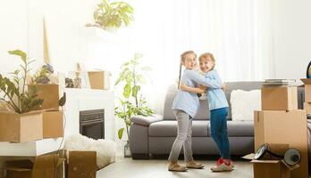 two little daughters celebrating moving day, excited by relocation into new house, laughing living room with cardboard boxes photo