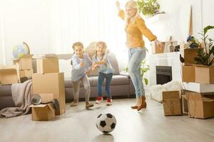 Pretty young mother and her cute little daughter having fun in new apartment and unpacking moving boxes photo