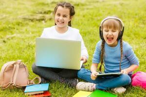 Two beautiful sisters do their homework during quarantine. Children use gadgets for learning. Education, distance learning, home schooling during quarantine photo