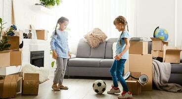 two little daughters celebrating moving day, excited by relocation into new house, laughing living room with cardboard boxes photo