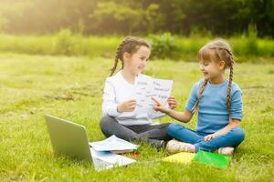 Pretty stylish schoolgirls studying online lesson in the courtyard, social distance during quarantine, self-isolation, online education concept photo