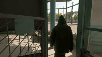 A young man in an incipient cloak and a respirator approaches a window in an old ruined building video