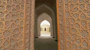 antiguo de madera puertas con oriental adornos abierto dentro un salón con columnas de el miriarab madrasa complejo. video