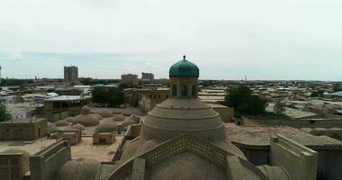 A drone flies over the MagokiAttari Mosque complex surrounded by old houses in Bukhara, Uzbekistan. Cloudy day. video