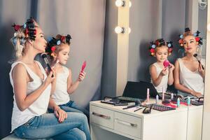 Mother and her child girl are doing your makeup and having fun n photo