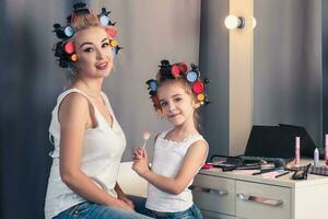 Mother and her child girl are doing your makeup and having fun photo