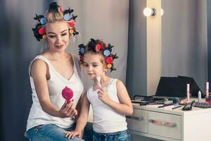 Mother and her child girl are doing your makeup and having fun photo