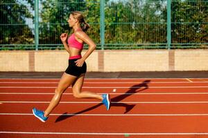 Side view beautiful young woman exercise jogging and running on athletic track on stadium photo