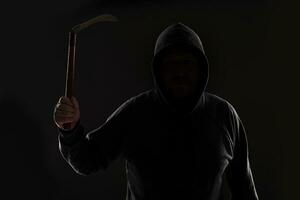 Criminal in dark clothes and balaclava with scythe photo