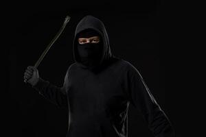 Male offender masked with a scrap. On black background at the studio photo