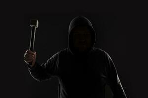 Criminal in dark clothes and balaclava with hammer photo