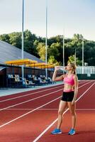 A young girl who participates in sport at the stadium drinking water photo