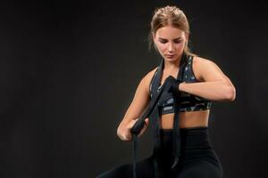 Young fit woman wrapping her arms with bandage tape. Attractive girl preparing for the kickboxing training. photo