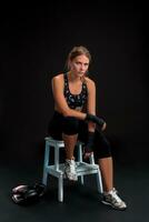 joven ajuste mujer mirando a el cámara mientras envase su brazos con vendaje cinta. atractivo niña preparando para el kickboxing capacitación. foto