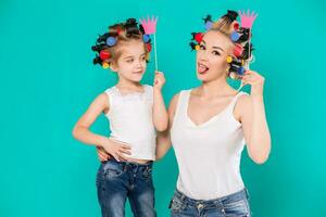 Funny family on a background of bright blue wall. Mother and her daughter girl with a paper accessories. photo