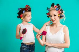 Mother and little daughter in hair curlers on a turquoise background in the studio photo