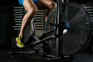 Side view close-up part of young man in sports shoes cycling at gym photo