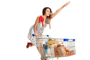 Woman with shopping cart full with products isolated over white background photo
