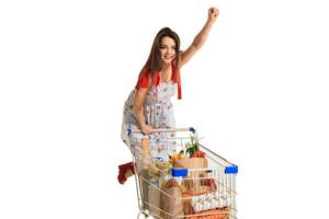 Woman with shopping cart full with products isolated over white background photo