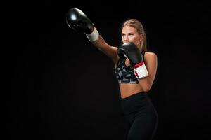 Beautiful female athlete in boxing gloves, in the studio on a black background. photo