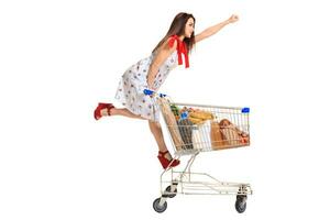 Woman with shopping cart full with products isolated over white background photo