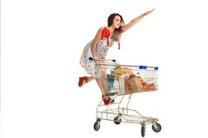 Woman with shopping cart full with products isolated over white background photo